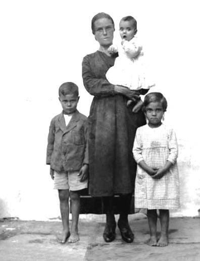 Una mujer de luto con sus tres hijos. Ella es la única que no está descalza.