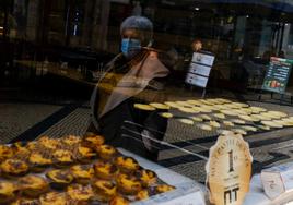 Una señora pasea con mascarilla junto a una pastelería en Portugal.