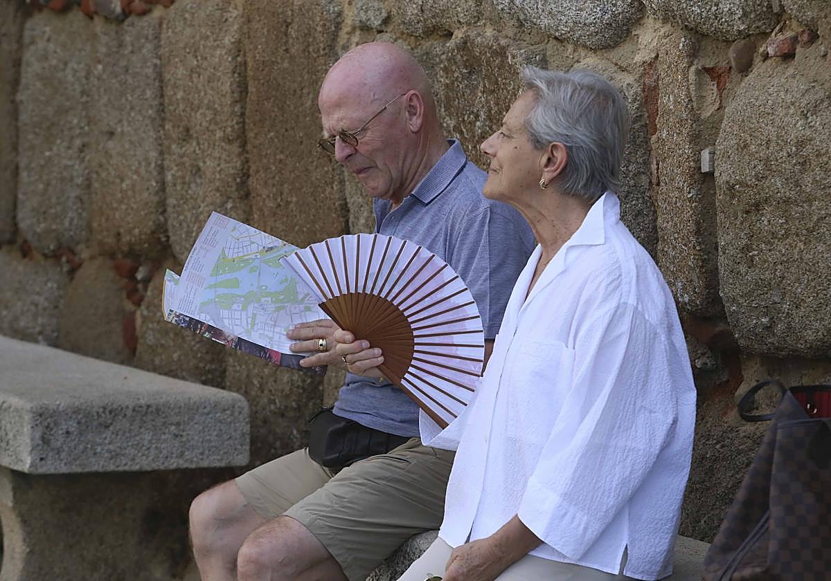 Una turista combate el calor con un abanico.