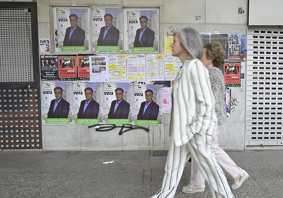 Dos mujeres pasan por delante de carteles de Parra como candidato este miércoles en Badajoz.