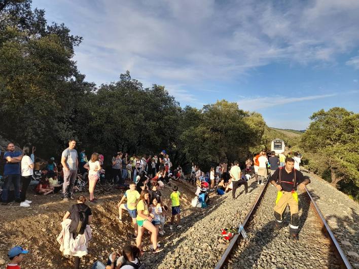 El grupo de niños y otros viajeros junto a las vías del tren.