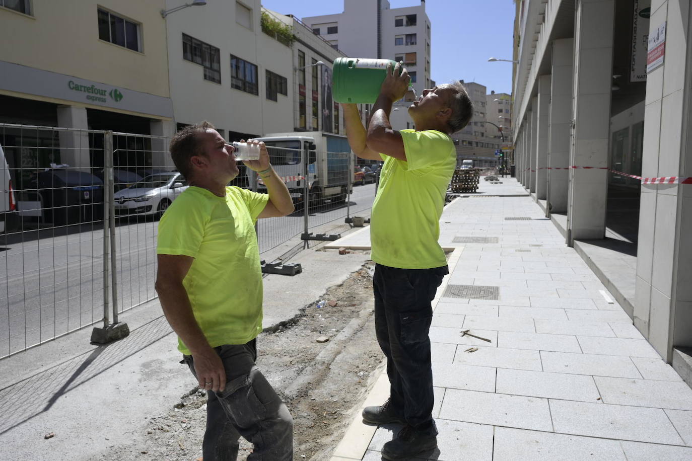 Dos trabajadores de la obra de Juan Carlos I se refrescan en una mañana donde el termómetro ha alcanzado los 40 grados