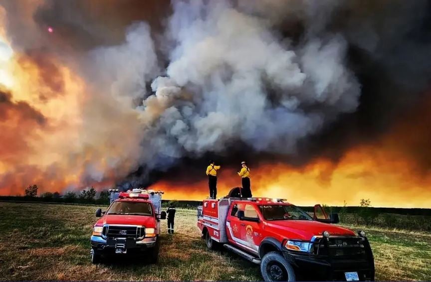 Bomberos observan las enormes dimensiones de las llamas que devoran Fort St. John, en la Columbia Británica.