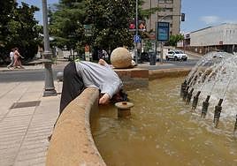 Un hombre se refresca en una fuente de la avenida de Huelva en Badajoz.