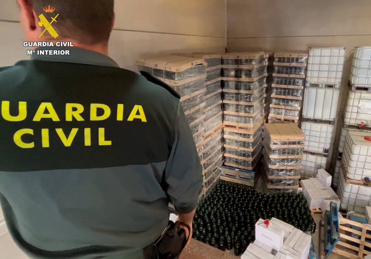 Un agente de la Guardia Civil en Sevilla junto a aceite decomisado por venderse como de virgen extra cuando no lo era.