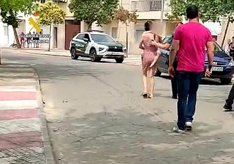 La víctima camina con su hijo en brazos.