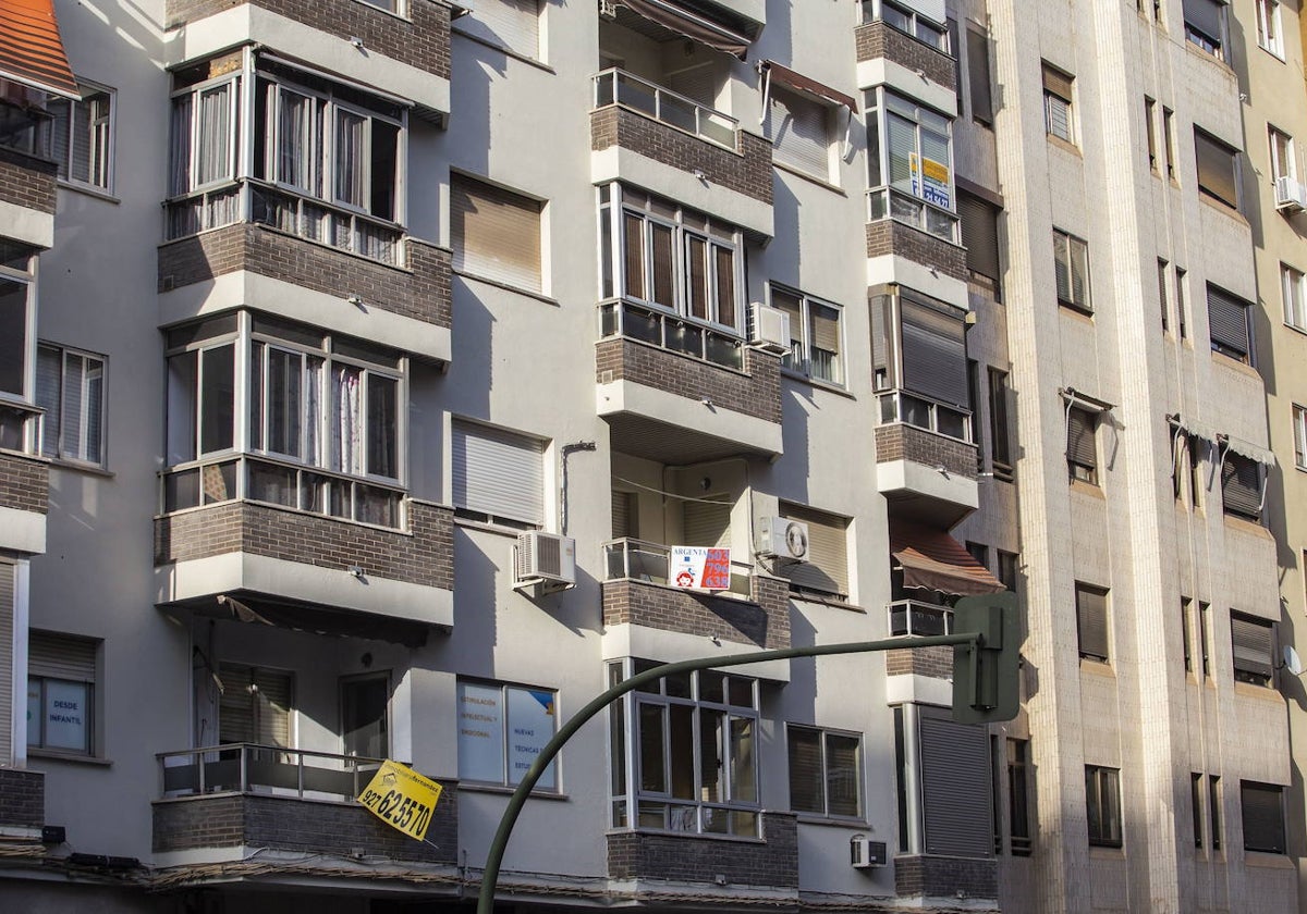 Bloque de viviendas en Cáceres con carteles de agencias inmobiliarias.