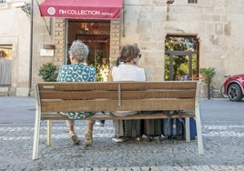 Dos turistas aguardan con sus maletas a las puertas del hotel NH Palacio de Oquendo de la Plaza de San Juan de Cáceres.