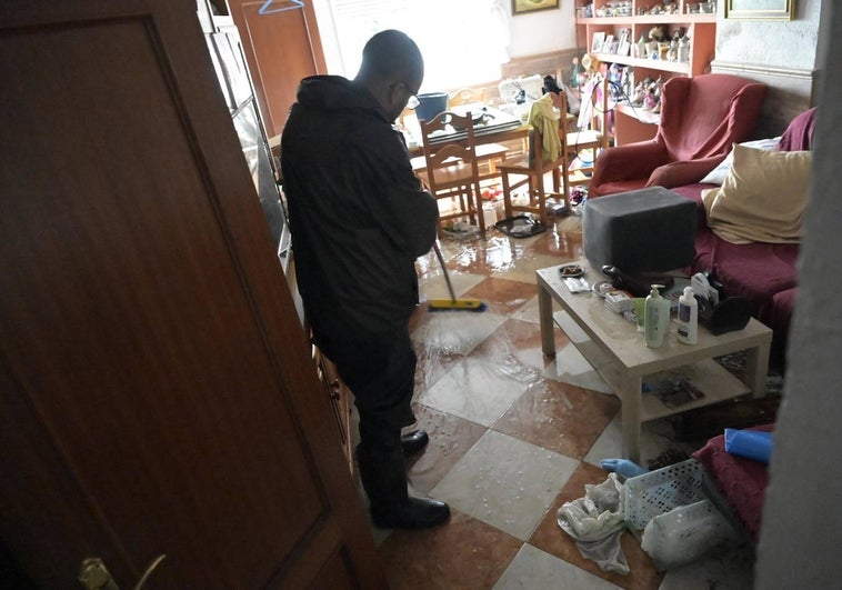 Un hombre saca agua de su casa en la barriada pacense de Las Moreras.