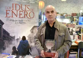 Javier Negrete, con un cartel promocional y un ejemplar de su novela histórica 'Los idus de enero'.