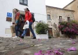 Dos viandantes pasan delante de un apartamento turístico situado en la calle Rincón de la Monja, en plena Ciudad Monumental de Cáceres.