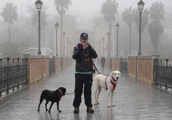 Un peatón hace una foto en el Puente de Palmas de Badajoz en medio de la niebla.
