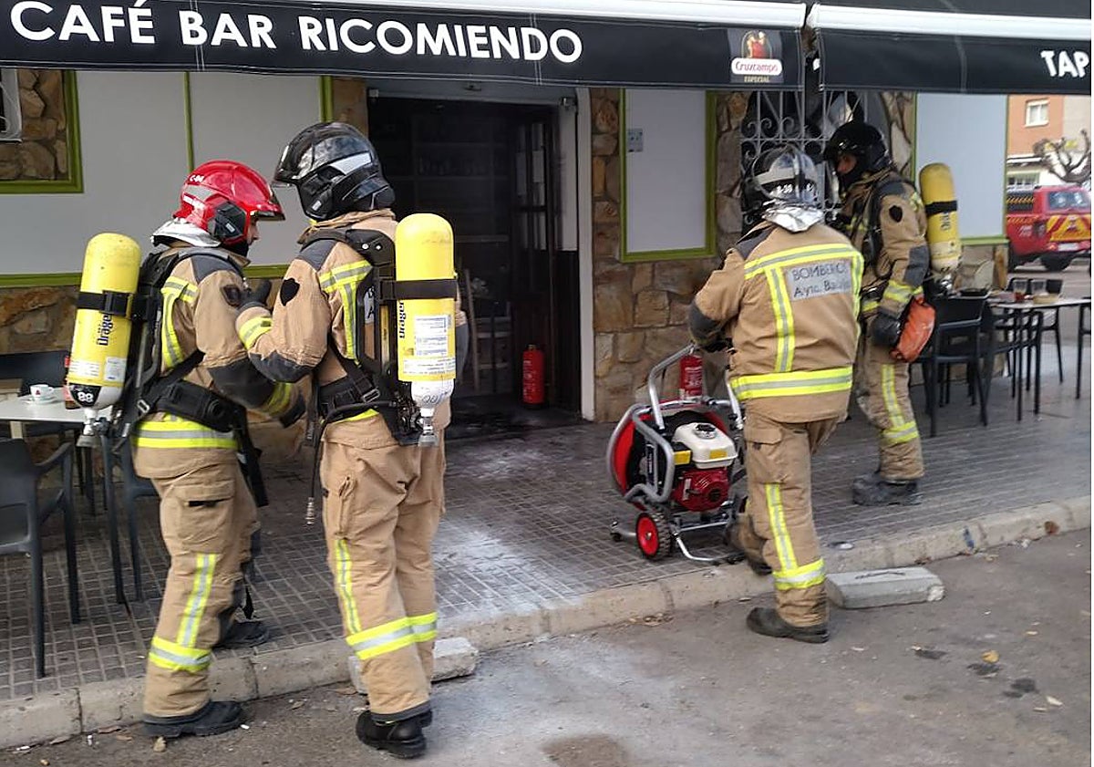 Imagen principal - Los bomberos durante la intervención, los extintores en la puerta, y la freidora, en una ventana del bar.