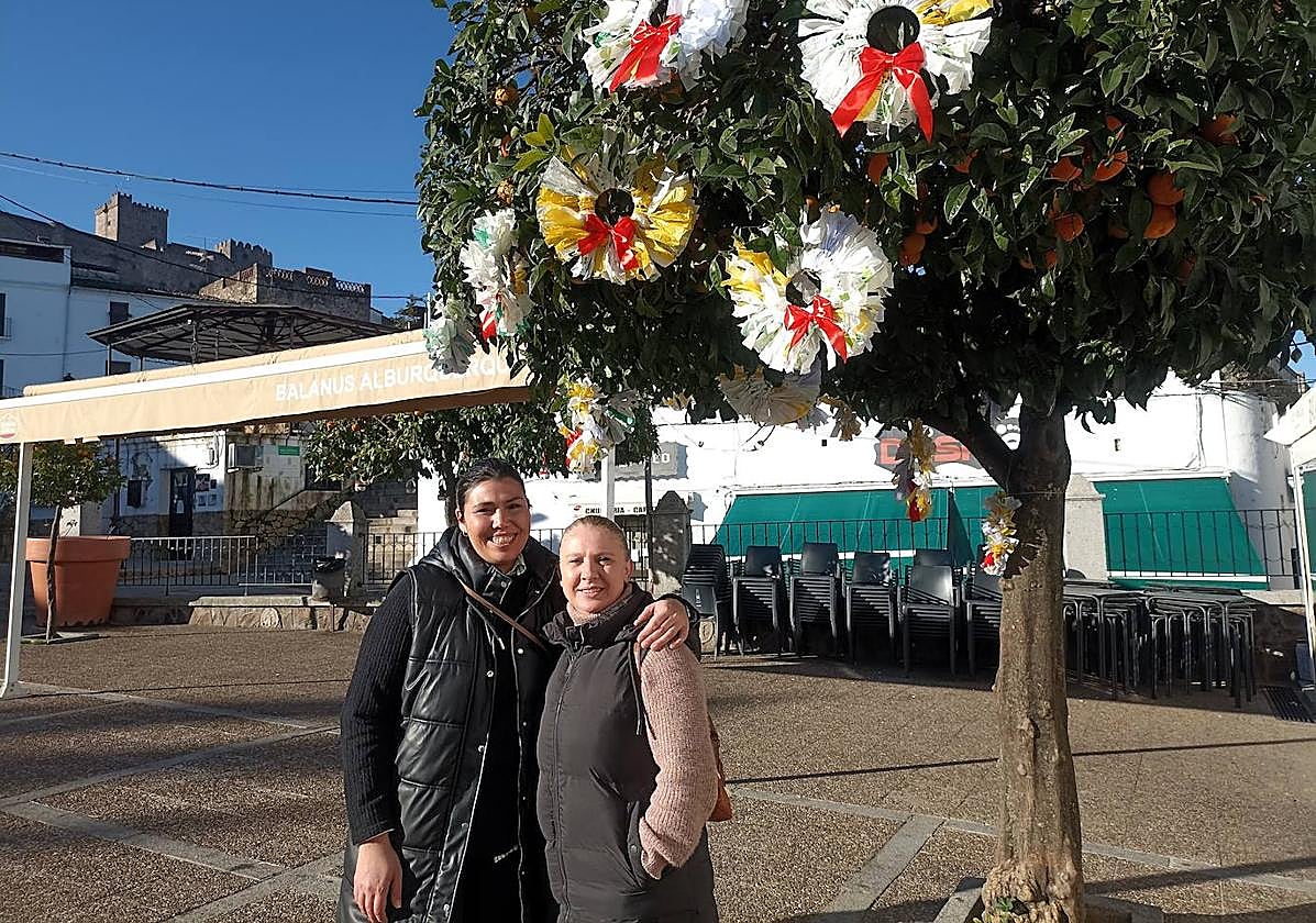 Victoria y Paqui bajo un naranjo del centro adornado con materiales reciclados