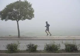 Un deportista corre con la densa niebla en el día de Navidad.