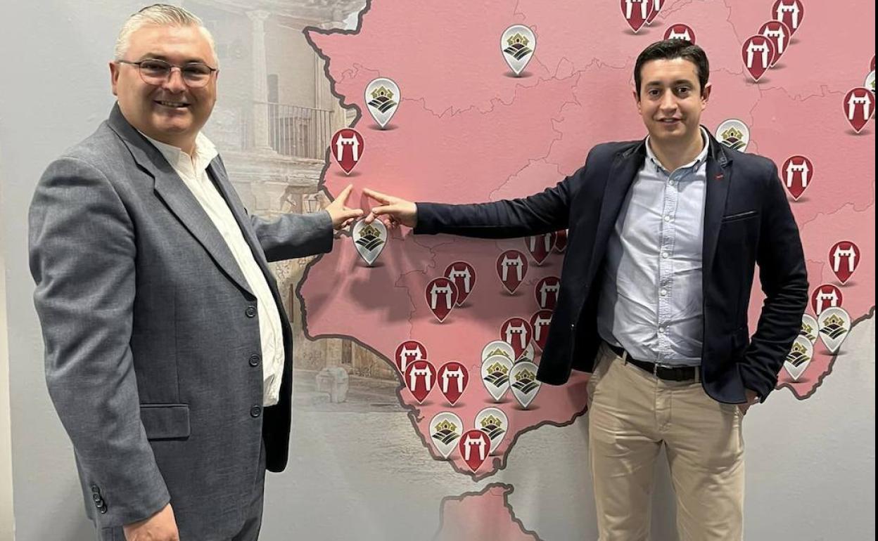 El alcalde y el concejal de Turismo, junto al panel de la Red de Castillos y Palacios de España que hay en FITUR 2023. 