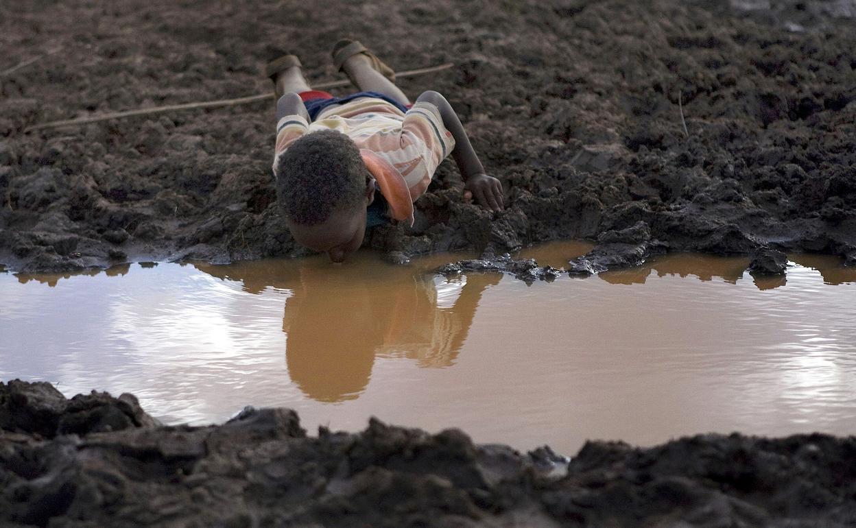 Un niño bebe agua de un charco en la aldea de Bule Duba, en Etiopía.