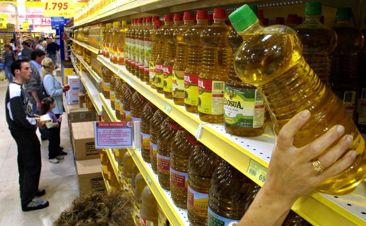 Un cliente coge una botella de aceite de un supermercado. 