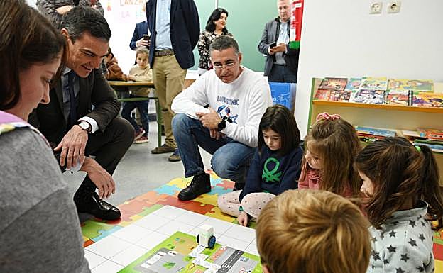 Pedro Sánchez ve cómo funciona un pequeño robot junto a los alumnos.