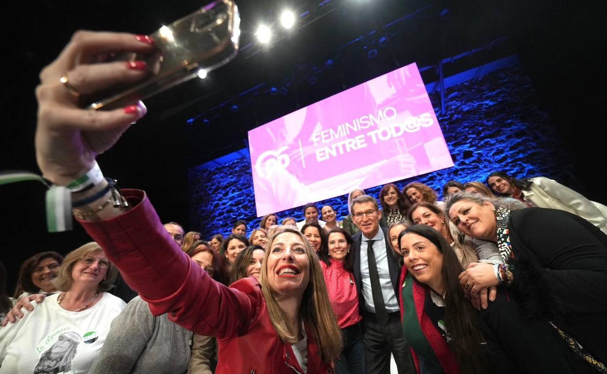 María Guardiola haciendo una foto a Alberto Núñez Feijóo y a mujeres que estaban en el escenario en un momento del acto en el Gran Teatro de Cáceres. 