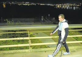 Un hombre pasea por el Puente Real con el parque del río con todas las farolas apagadas al fondo.