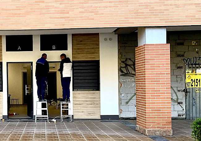 Dos operarios ultiman los detalles para la colocación de las letras A y B en dos apartamentos obtenidos de un local comercial a la altura del 31 de Avenida de Alemania. Al lado, otro local sin uso en la actualidad.