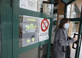 Una mujer saliendo de un centro de salud de Cáceres con mascarilla.