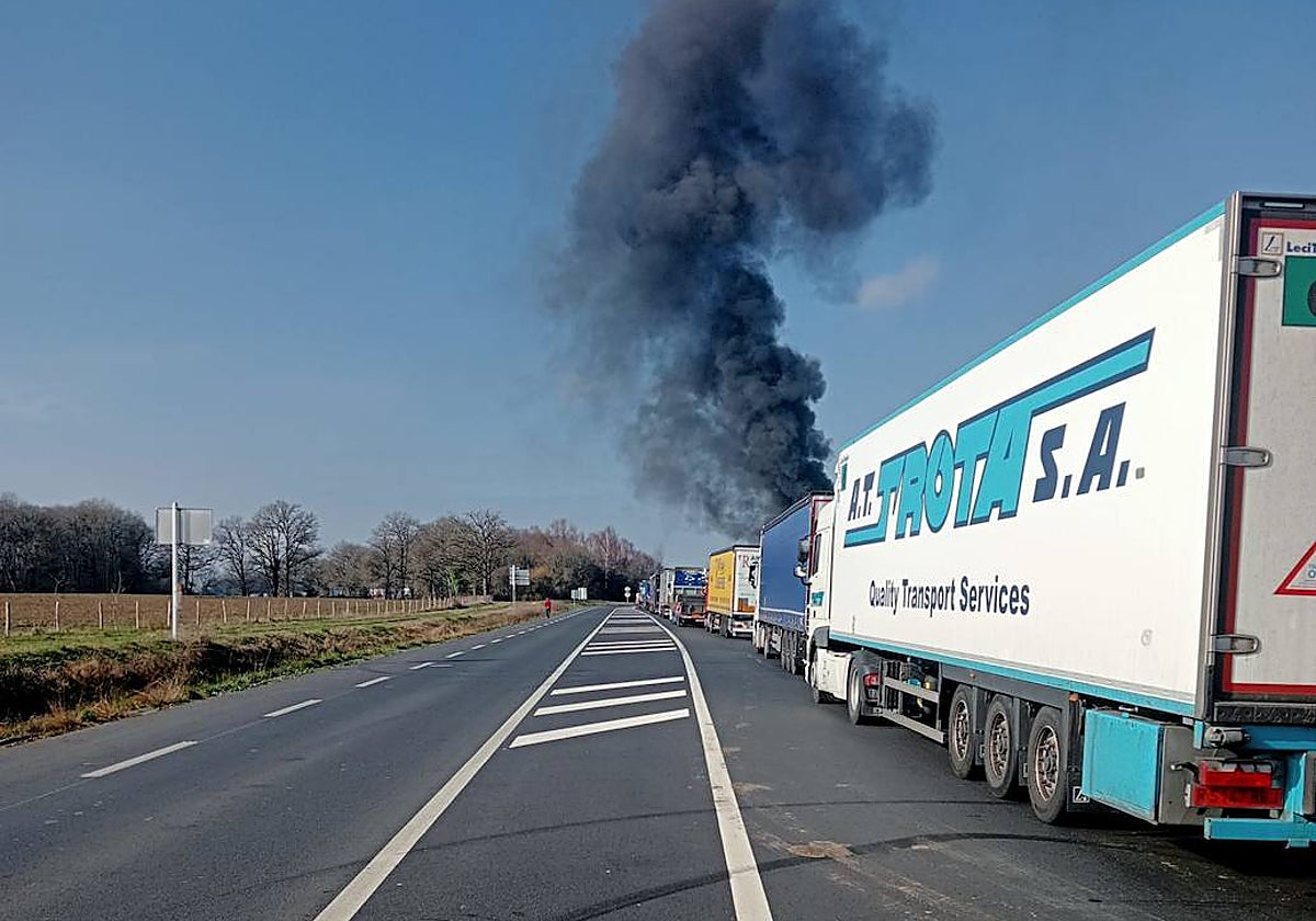 Camiones retenidos en la localidad francesa de Angulema y, al fondo, una hoguera en un cruce cercano, ayer.