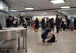 Pasajeros esperando en la estación de Atocha, en Madrid, tras anunciarse la demora de un tren con destino a Puertollano.