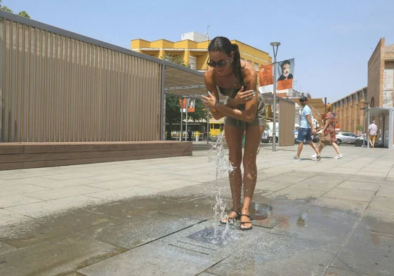 Una joven se refresca en una fuente de Mérida en un día del mes de julio.