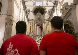 Dos costaleros rezan delante de la Virgen del Rosario.