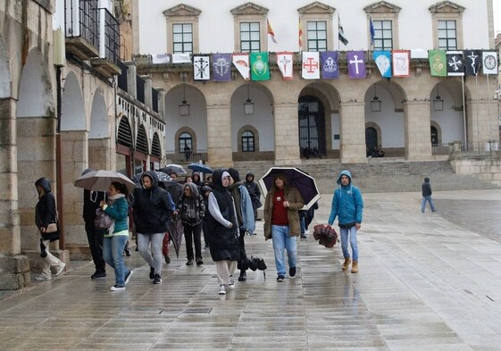Un grupo de personas paseando por la Plaza Mayor de Cáceres la semana pasada bajo la lluvia.