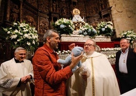 Momento en el que un padre presenta a su bebé a la patrona de Cáceres y recibe la bendición de manos del deán de la Concatedral de Santa María.