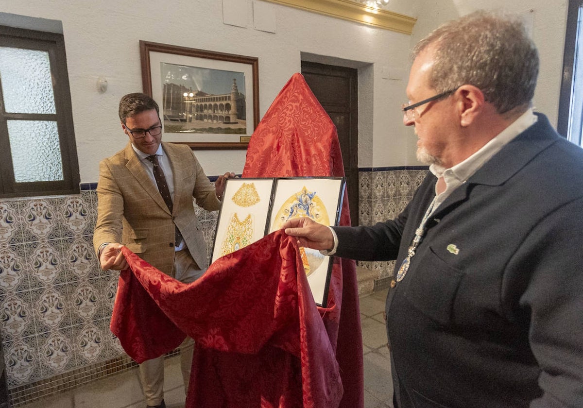 El concejal de Cultura y el mayordomo de la cofradía muestran el boceto del manto del centenario.