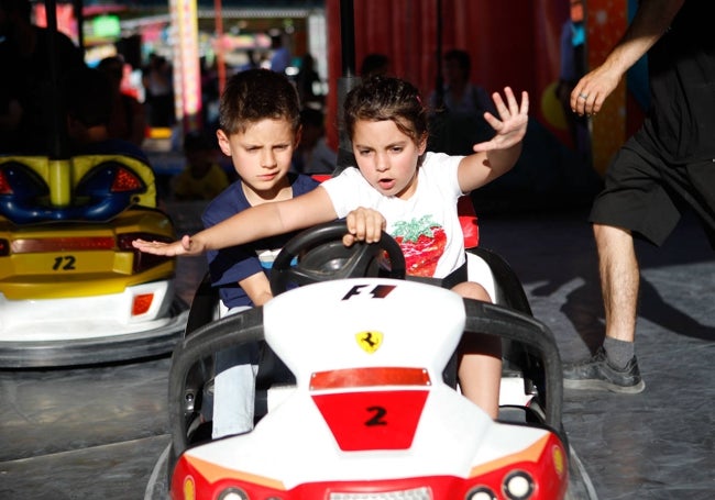 Dos niños disfrutan de los coches de choque, un clásico de la Feria.