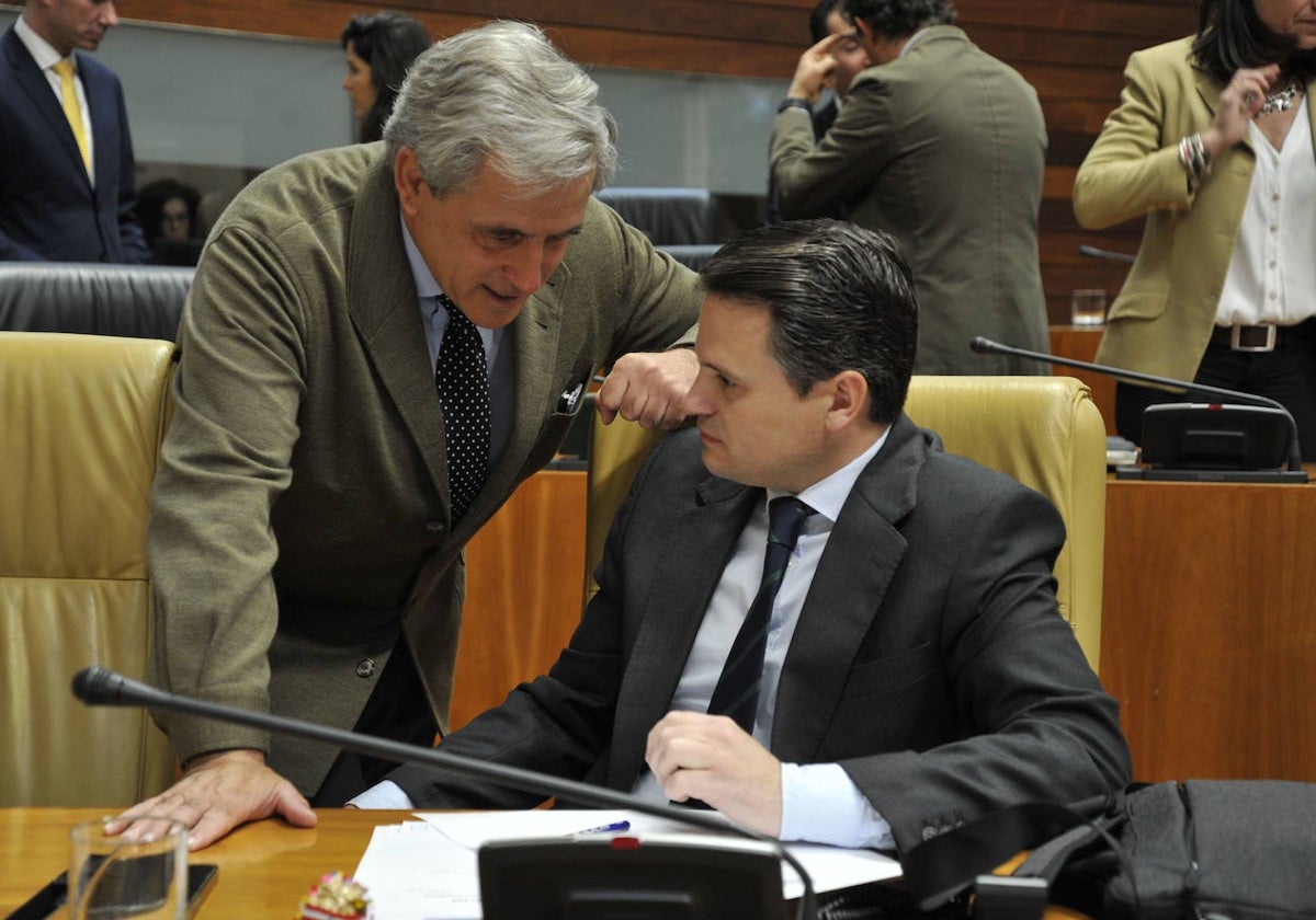 Ignacio Higuero (izda), consejero de Gestión Forestal y Mundo Rural, charla con Abel Bautista, consejero de Presidencia, en la Asamblea de Extremadura.