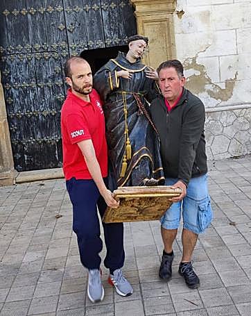 El párroco, junto a un colaborador, portando la imagen de San Antonio en los preparativos de la misa de campaña