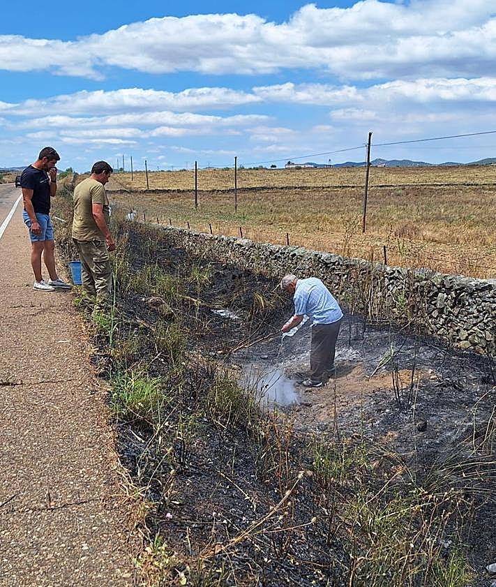 Imagen secundaria 2 - Arriba, bomberos y vecinos voluntarios, haciendo labores de extinción terrestres en la finca más afectada. Abajo, varios vecinos de Alconchel, sofocando otro foco aislado junto a la carretera.