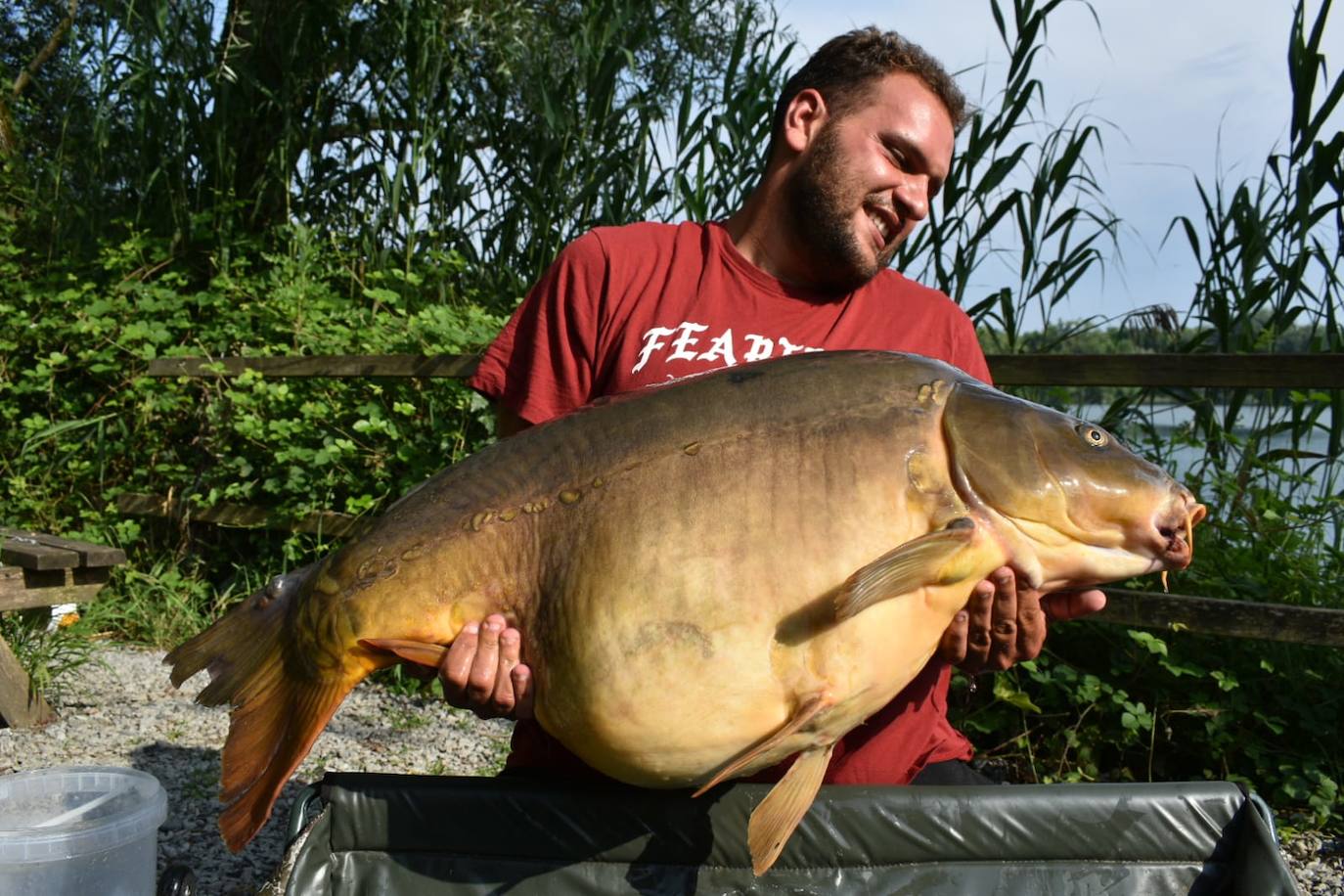 Jairo Canchado, cogiendo en peso la gran carpa que ha capturado junto a su amigo Alberto Cacho.