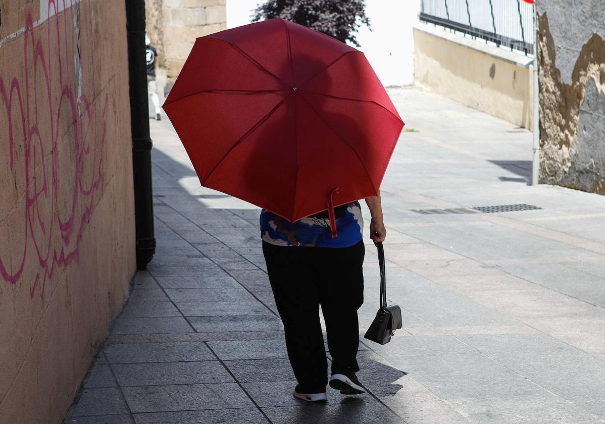 Una mujer pasea por Cáceres bajo un paraguas para aplacar el sofocante calor.