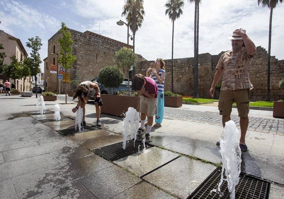 Una familia de turistas se refresca junto a la Alcazaba de Mérida, poco después del mediodía.