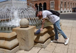 Una persona se refresca en una fuente en la avenida de Huelva, en Badajoz.