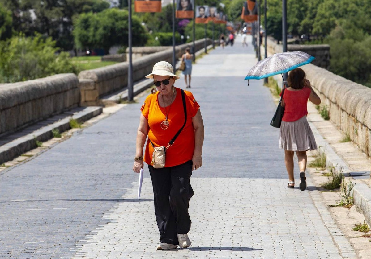 Una mujer camina por el Puente Romano de Mérida en un día de altas temperaturas.