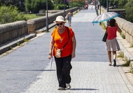 Una mujer camina por el Puente Romano de Mérida en un día de altas temperaturas.