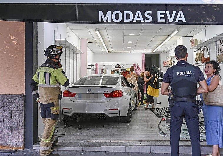 Eva, la propietaria de la tienda, junto a un policía local, y el coche dentro del local.