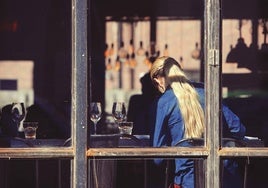 Fotografía de una mujer de espaldas en un local de hostelería.