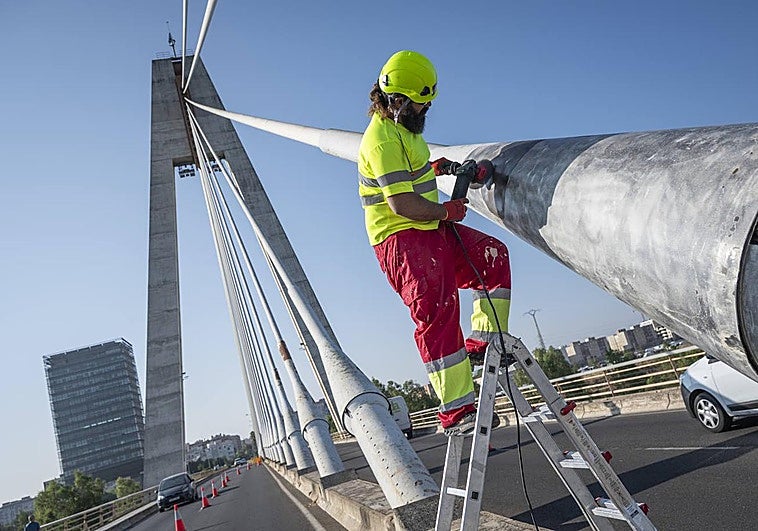 Uno de los operarios lija los capuchones del puente antes de pintarlo.