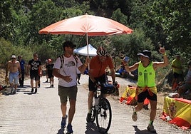 Dos aficionados animan y protegene del sol a un ciclista que se ha atrevido a subir al Pico Villuercas.
