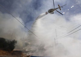 Un helicóptero vacía su helibalde en un incendio en Cáceres.