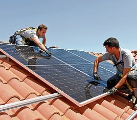 Unos operarios instalan paneles solares en el tejado de una vivienda.